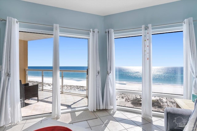 entryway featuring a wealth of natural light, a water view, and a view of the beach