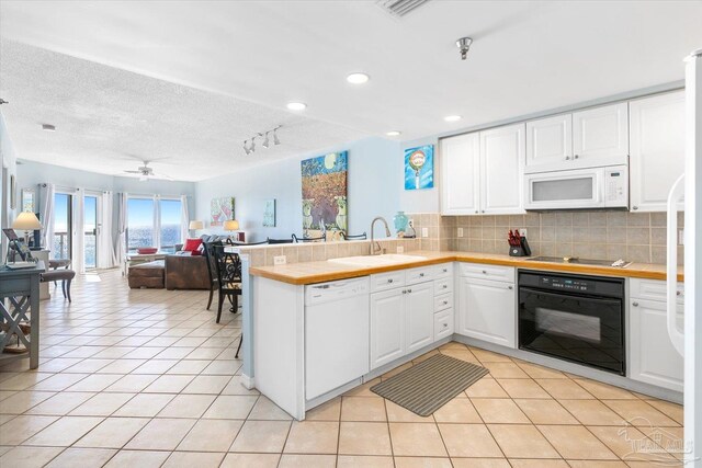 kitchen with white appliances, sink, kitchen peninsula, and white cabinets