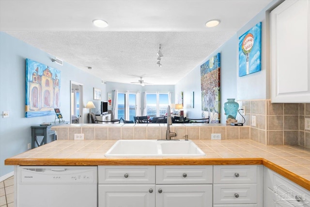 kitchen featuring sink, dishwasher, kitchen peninsula, and tile counters