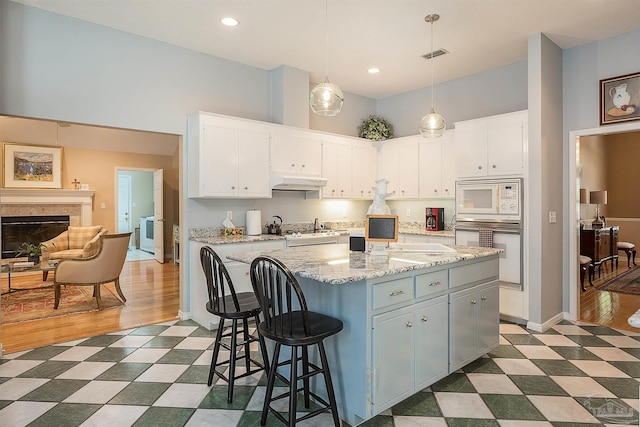 4200 Madura Rd, Gulf Breeze, FL 32563 - kitchen featuring white cabinets, dark floors, visible vents, under cabinet range hood, and white appliances
