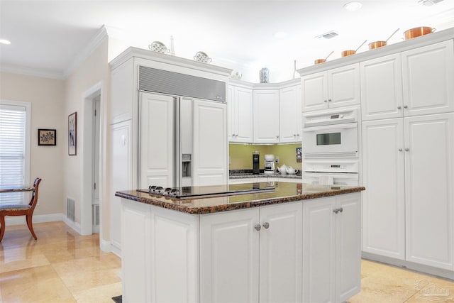 kitchen featuring paneled built in refrigerator, ornamental molding, white cabinets, and black electric cooktop