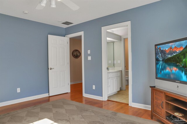 bedroom with ensuite bath, light hardwood / wood-style floors, and ceiling fan