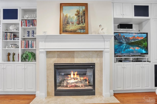 living room featuring built in shelves, a fireplace, and light wood-type flooring