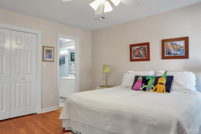 bedroom featuring ceiling fan, ensuite bathroom, a closet, and light hardwood / wood-style flooring