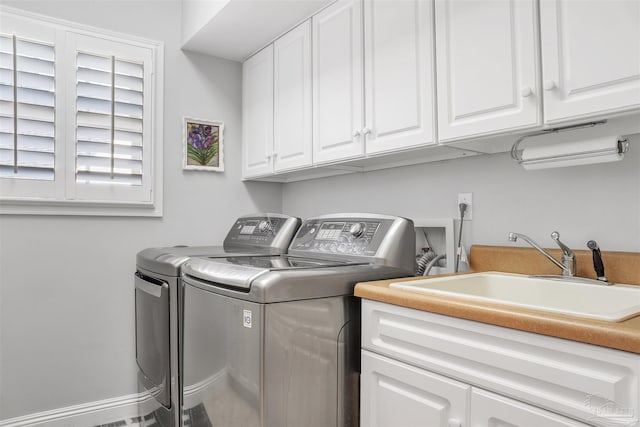 laundry area featuring sink, washing machine and dryer, and cabinets