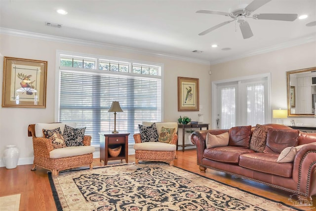 living room featuring hardwood / wood-style flooring, ornamental molding, and ceiling fan