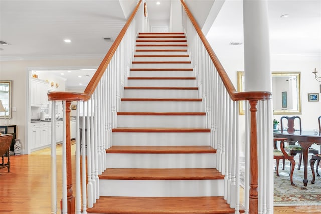 stairway with crown molding and hardwood / wood-style flooring