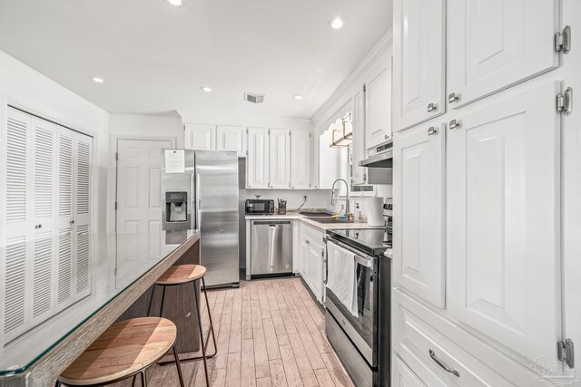 kitchen featuring light hardwood / wood-style flooring, white cabinets, appliances with stainless steel finishes, and sink