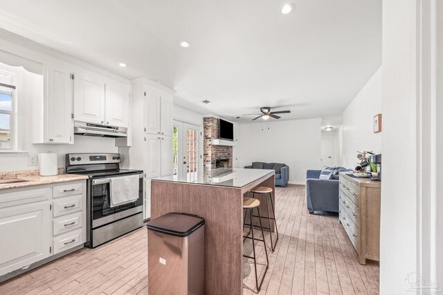 kitchen with light wood-type flooring, a fireplace, white cabinetry, and stainless steel electric range oven