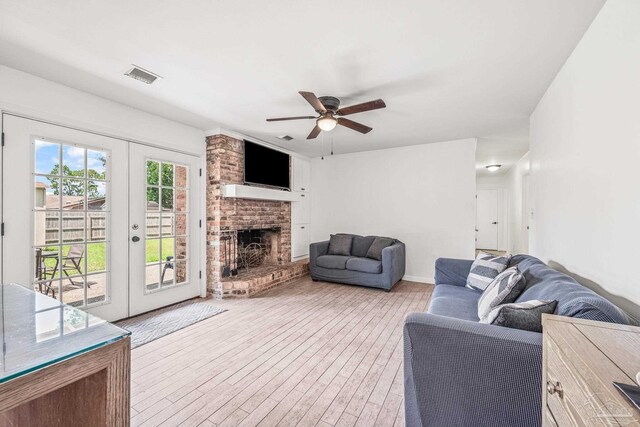 living room featuring a fireplace, ceiling fan, and french doors