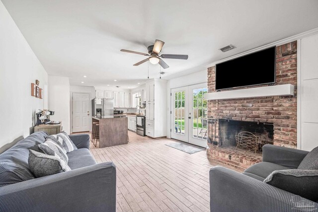 living room with light hardwood / wood-style flooring, a brick fireplace, and ceiling fan