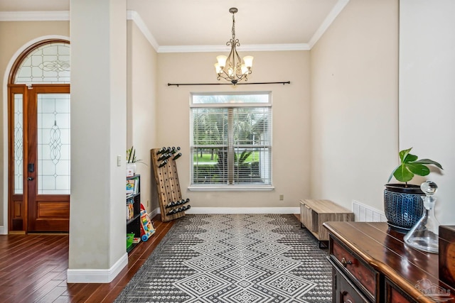 foyer entrance with ornamental molding, dark wood-type flooring, and a chandelier