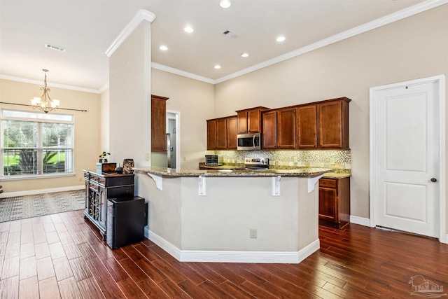 kitchen with kitchen peninsula, a kitchen bar, appliances with stainless steel finishes, dark hardwood / wood-style flooring, and light stone countertops