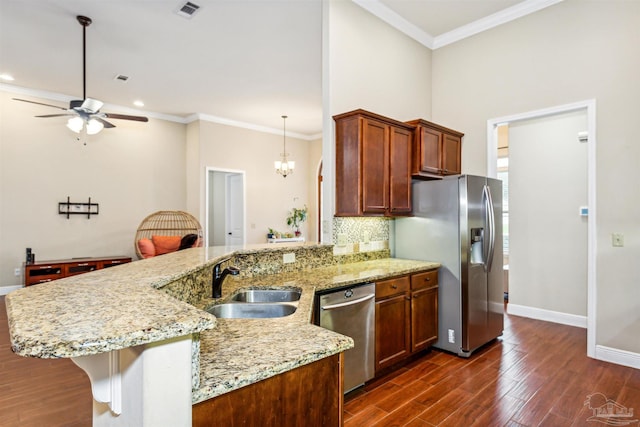 kitchen with dark hardwood / wood-style floors, sink, ceiling fan with notable chandelier, hanging light fixtures, and appliances with stainless steel finishes