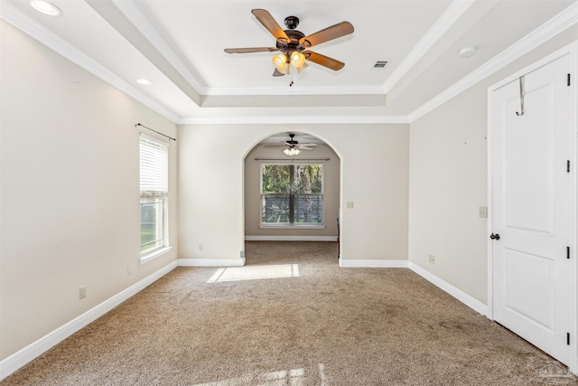 unfurnished room featuring a raised ceiling, carpet flooring, crown molding, and ceiling fan