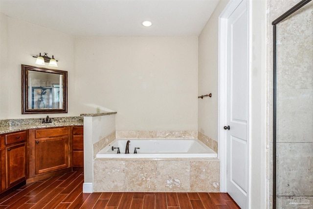 bathroom featuring vanity, tiled bath, and hardwood / wood-style floors