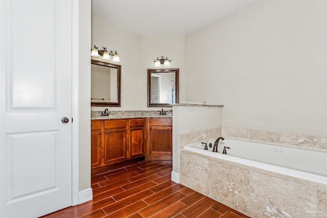 bathroom with a relaxing tiled tub, vanity, and hardwood / wood-style floors