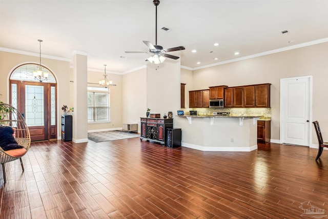 kitchen with light stone counters, dark hardwood / wood-style floors, ceiling fan with notable chandelier, kitchen peninsula, and a kitchen breakfast bar