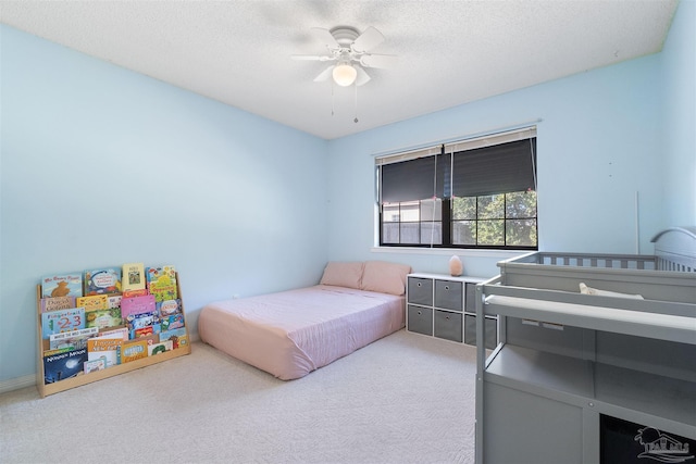 carpeted bedroom featuring ceiling fan and a textured ceiling