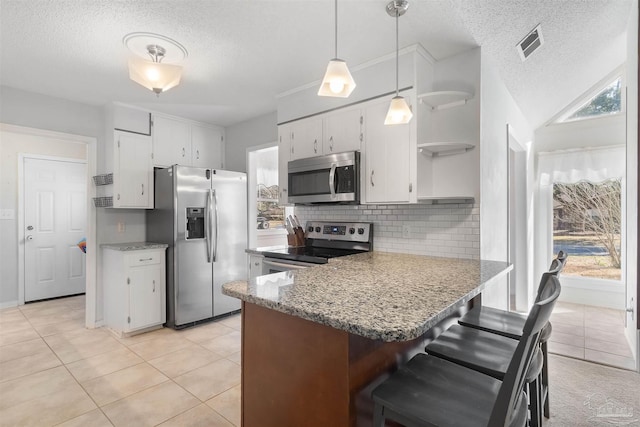 kitchen featuring pendant lighting, appliances with stainless steel finishes, white cabinetry, light stone counters, and decorative backsplash