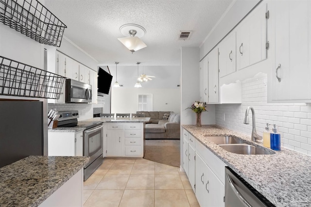 kitchen featuring sink, white cabinetry, backsplash, stainless steel appliances, and decorative light fixtures