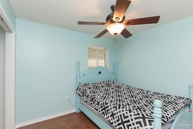 bedroom with ceiling fan, dark hardwood / wood-style floors, and a textured ceiling