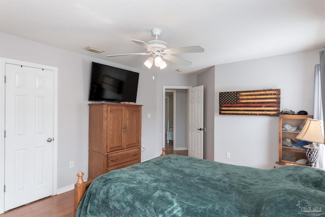 bedroom with a textured ceiling, wood-type flooring, and ceiling fan