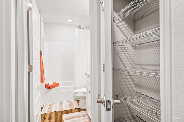 bathroom featuring shower / bath combo, hardwood / wood-style flooring, and toilet