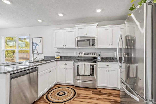 kitchen featuring white cabinets, dark stone countertops, sink, and stainless steel appliances