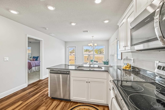 kitchen with pendant lighting, white cabinets, sink, stainless steel appliances, and a chandelier