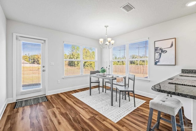 dining room with plenty of natural light, wood-type flooring, and an inviting chandelier