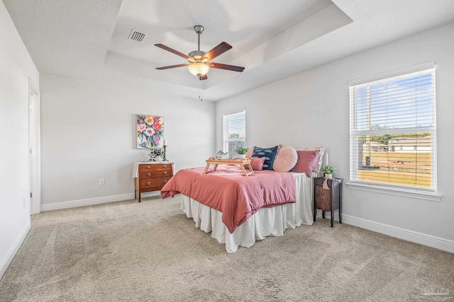 bedroom with carpet flooring, a raised ceiling, and ceiling fan