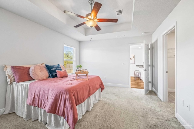 carpeted bedroom with a raised ceiling and ceiling fan