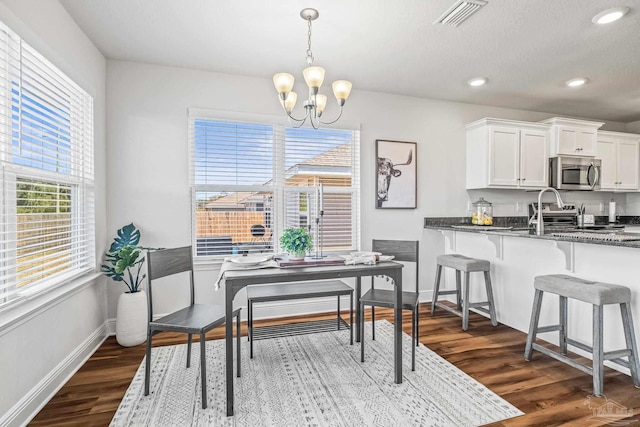 dining space featuring plenty of natural light, dark wood-type flooring, and an inviting chandelier