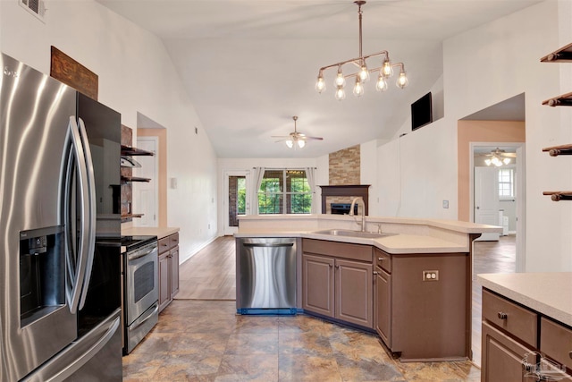 kitchen featuring light hardwood / wood-style flooring, ceiling fan, appliances with stainless steel finishes, a stone fireplace, and sink