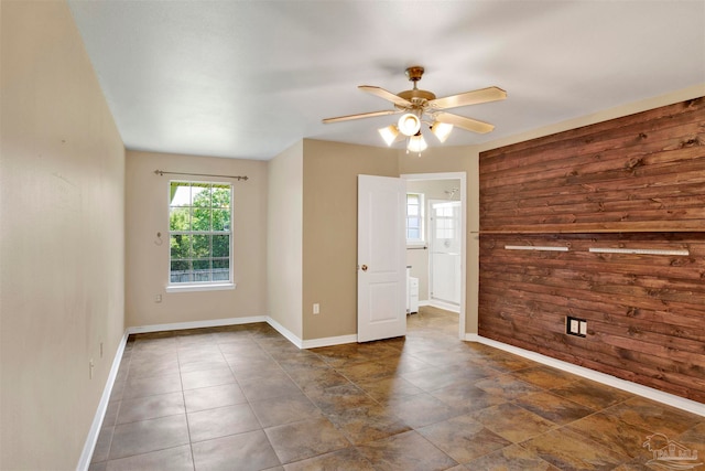 spare room featuring dark tile patterned floors, wood walls, and ceiling fan