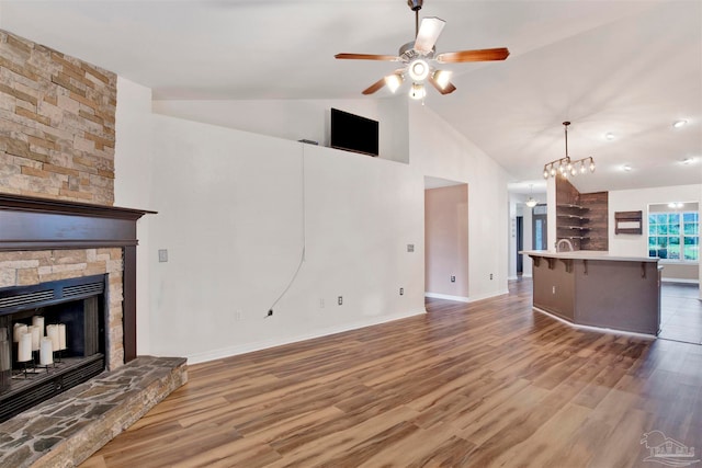 unfurnished living room with light hardwood / wood-style floors, a stone fireplace, high vaulted ceiling, and ceiling fan