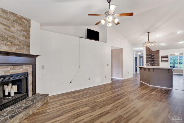 unfurnished living room featuring a fireplace, lofted ceiling, dark hardwood / wood-style floors, and ceiling fan