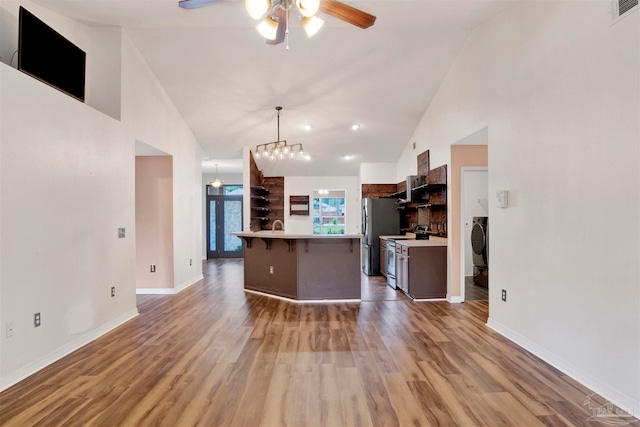 kitchen featuring stainless steel appliances, ceiling fan with notable chandelier, a kitchen island, a breakfast bar, and light hardwood / wood-style flooring