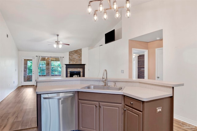 kitchen with vaulted ceiling, sink, a fireplace, light wood-type flooring, and dishwasher