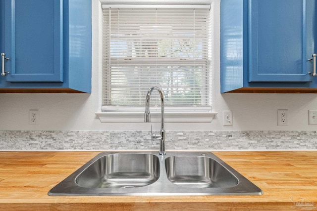 room details with blue cabinetry, sink, and butcher block countertops