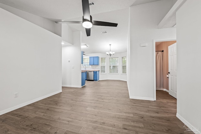 unfurnished living room with hardwood / wood-style flooring, vaulted ceiling, and ceiling fan with notable chandelier