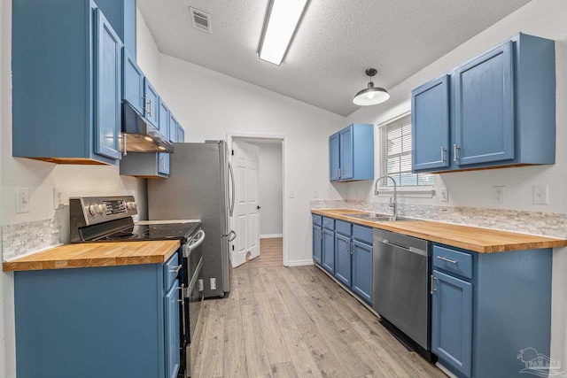 kitchen with blue cabinetry, lofted ceiling, sink, butcher block countertops, and appliances with stainless steel finishes