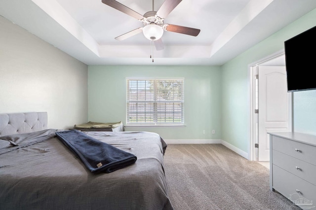 bedroom with a tray ceiling, baseboards, carpet floors, and ceiling fan