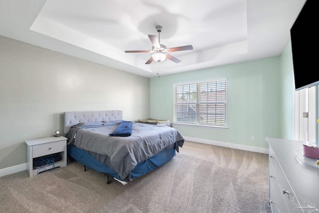 bedroom with a tray ceiling, a ceiling fan, baseboards, and light carpet