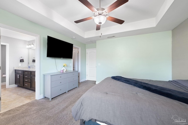 bedroom featuring a raised ceiling, light colored carpet, visible vents, and baseboards