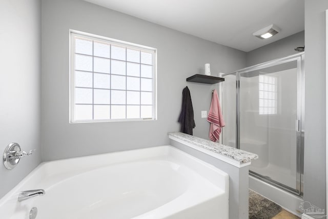 full bath featuring plenty of natural light, a garden tub, and a stall shower