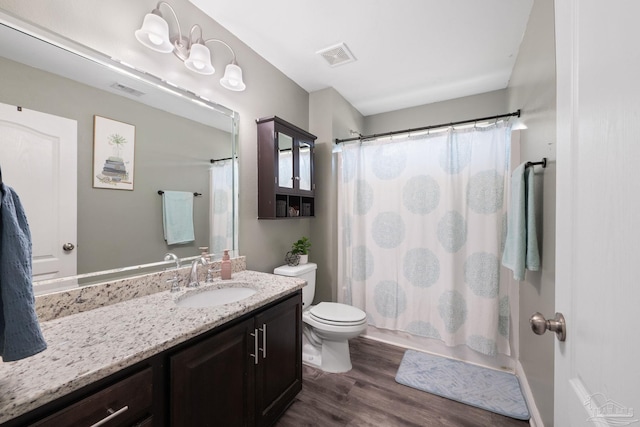 bathroom with visible vents, toilet, a shower with shower curtain, wood finished floors, and vanity