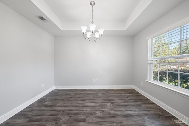 spare room with baseboards, visible vents, dark wood-style flooring, a raised ceiling, and a notable chandelier