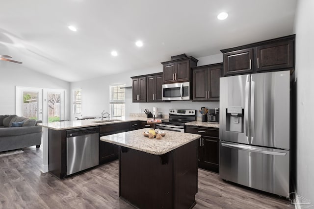 kitchen featuring dark brown cabinets, open floor plan, lofted ceiling, appliances with stainless steel finishes, and a peninsula